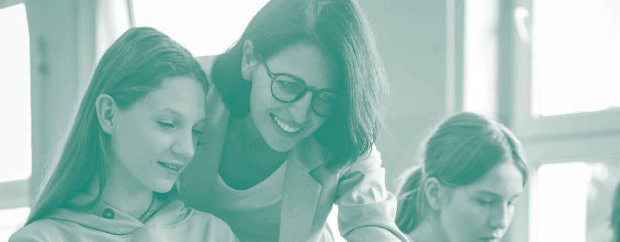 En lærer viser en elev noe på en laptop. Illustrasjonsbilde.