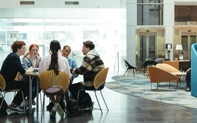 En gruppe studenter sitter rundt et bord og diskuterer. Illustrasjonsfoto.