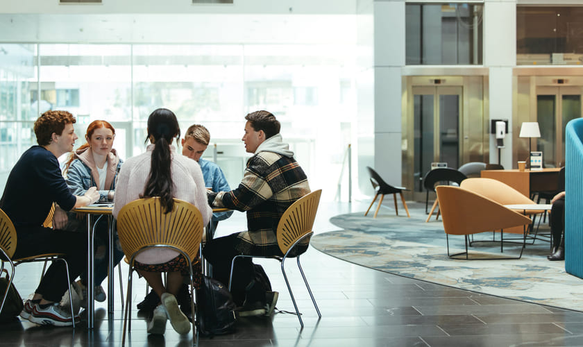 En gruppe studenter sitter rundt et bord og diskuterer. Illustrasjonsfoto.