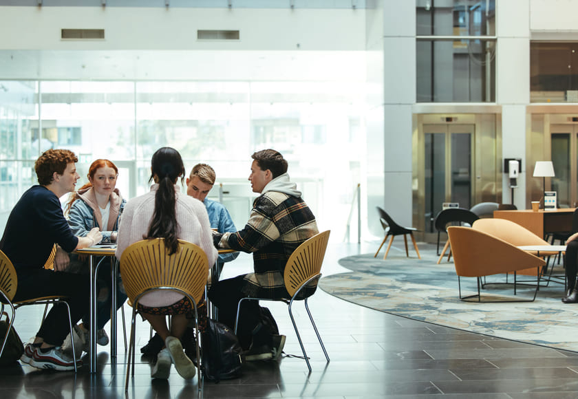 En gruppe studenter sitter rundt et bord og diskuterer. Illustrasjonsfoto.