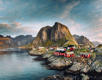 En samling av tradisjonelle hus i havgapet, fjellene troner i bakgrunnen.