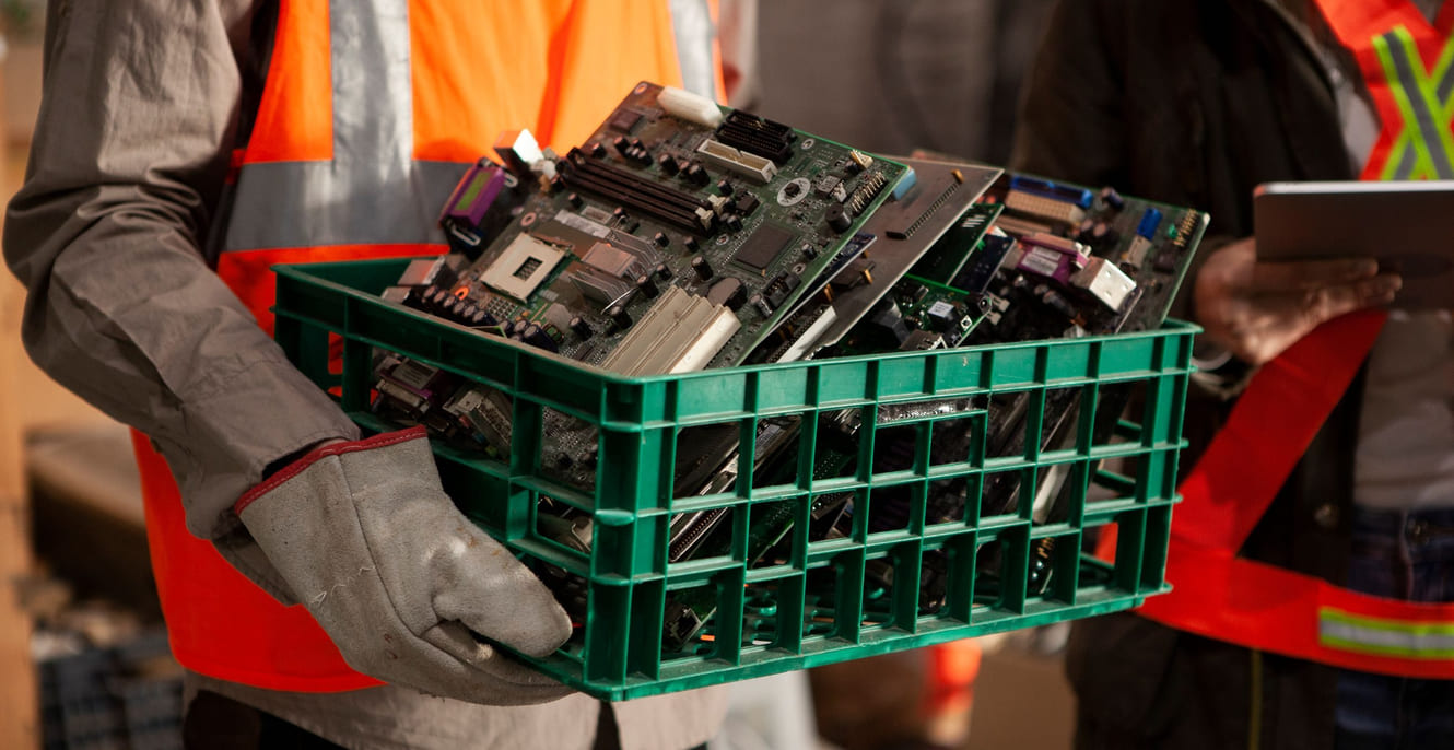 En mann som holder en kasse full av elektronisk avfall.