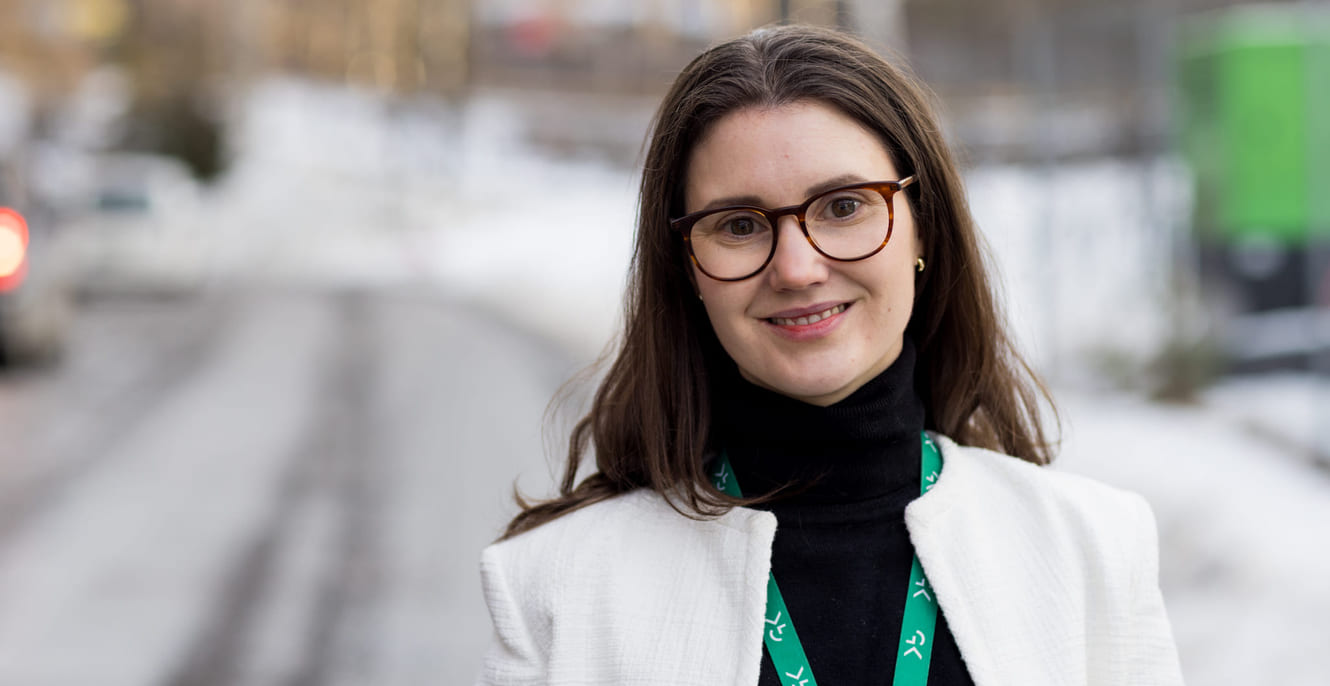 En kvinne med briller og hvit jakke som står på en snødekt gate.