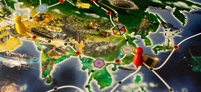 Nærbilde av et strategibrettspillkart med fargede spillebrikker på illustrert terreng, med markerte ruter, ikoner og merkede sekskantede felter.