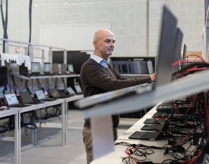 Skallet mann som jobber med laptoper i et fabrikklokale.