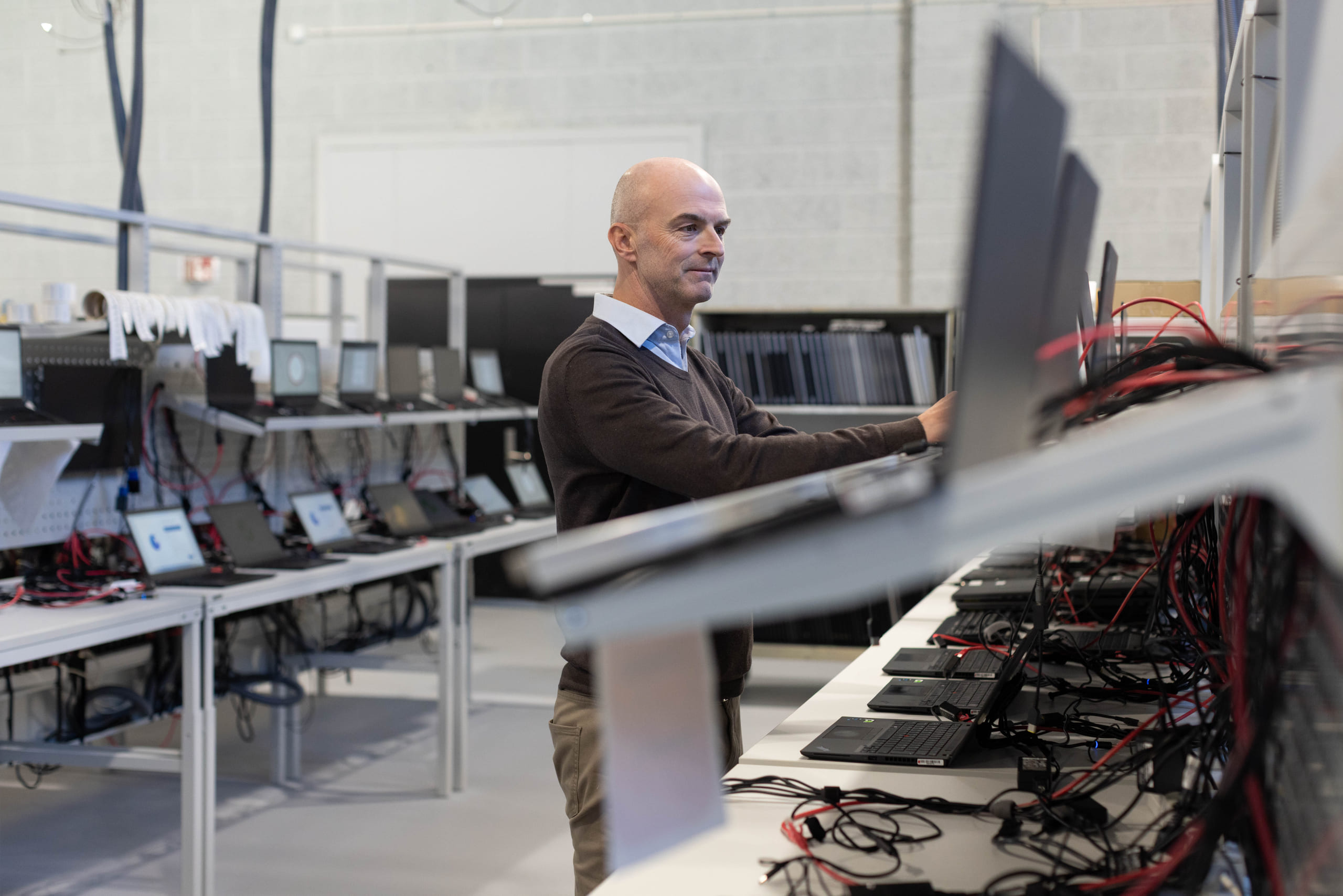 Skallet mann som jobber med laptoper i et fabrikklokale.