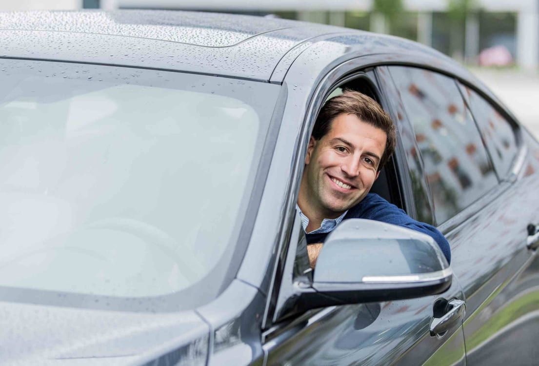 Ekspert på lån og renter, Henrik Eriksen, Santander Consumer Bank, sitter på førersiden i en bil, smiler og ser ut av vinduet