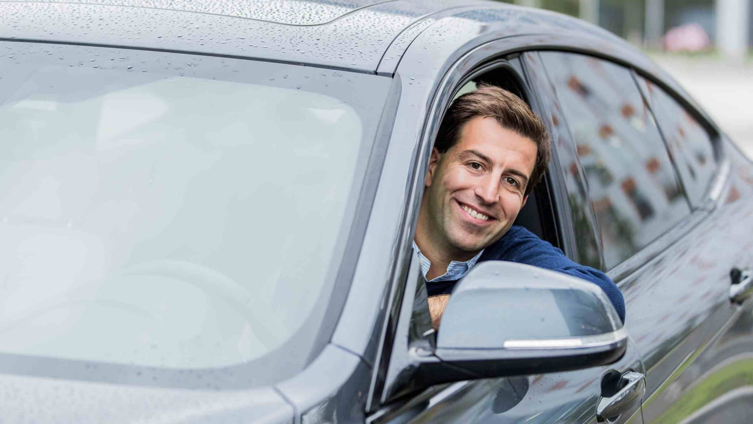 Ekspert på lån og renter, Henrik Eriksen, Santander Consumer Bank, sitter på førersiden i en bil, smiler og ser ut av vinduet