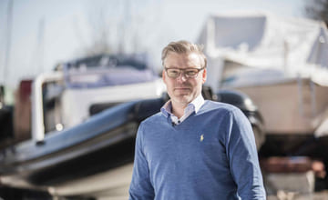 Båtentusiast står foran en RIB som er tatt opp på land