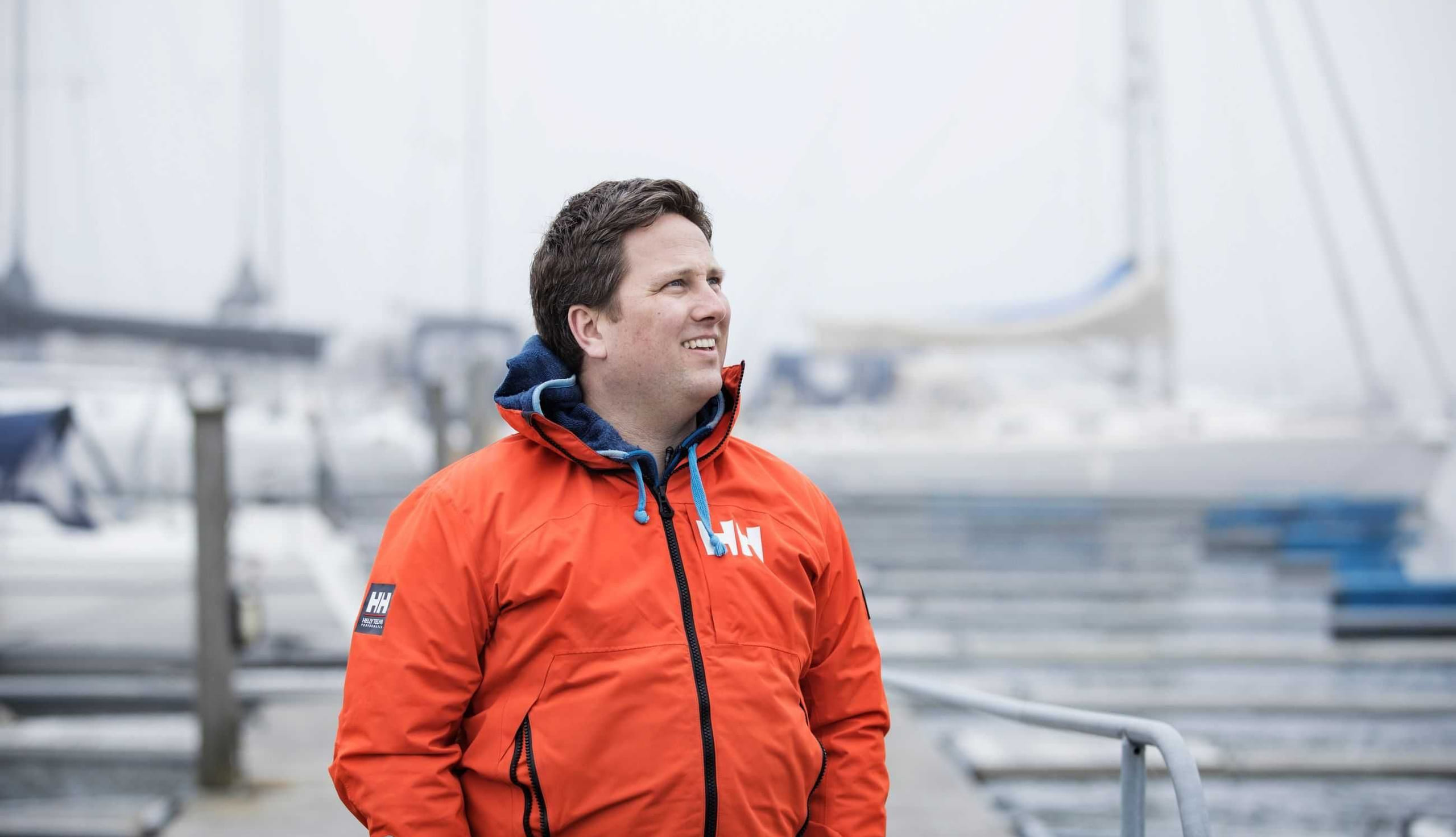 Mann står foran brygge med seilbåter