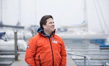 Mann står foran brygge med seilbåter