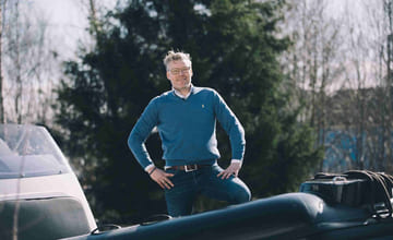 mann stå bak RIB-en han eier, plassert på land