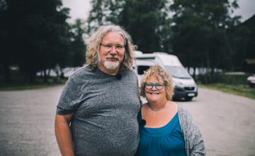 Par med bobil i bakgrunn