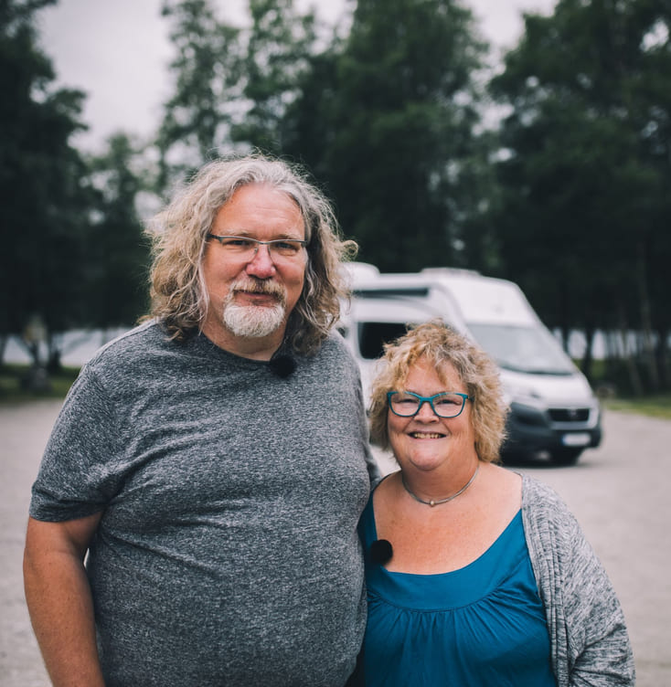 Par med bobil i bakgrunn