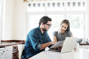 Par sitter med laptop for å opprette sparekonto