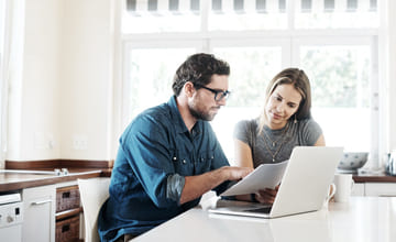 Par sitter med laptop for å opprette sparekonto