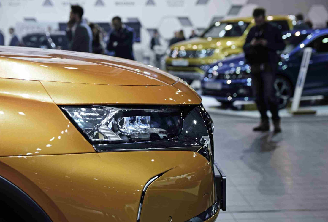 Fronten av en gullfarget bil som står inne i en bilbutikk