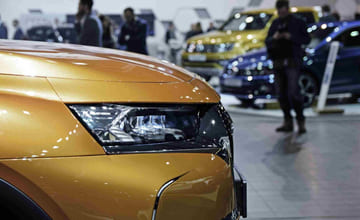 Fronten av en gullfarget bil som står inne i en bilbutikk