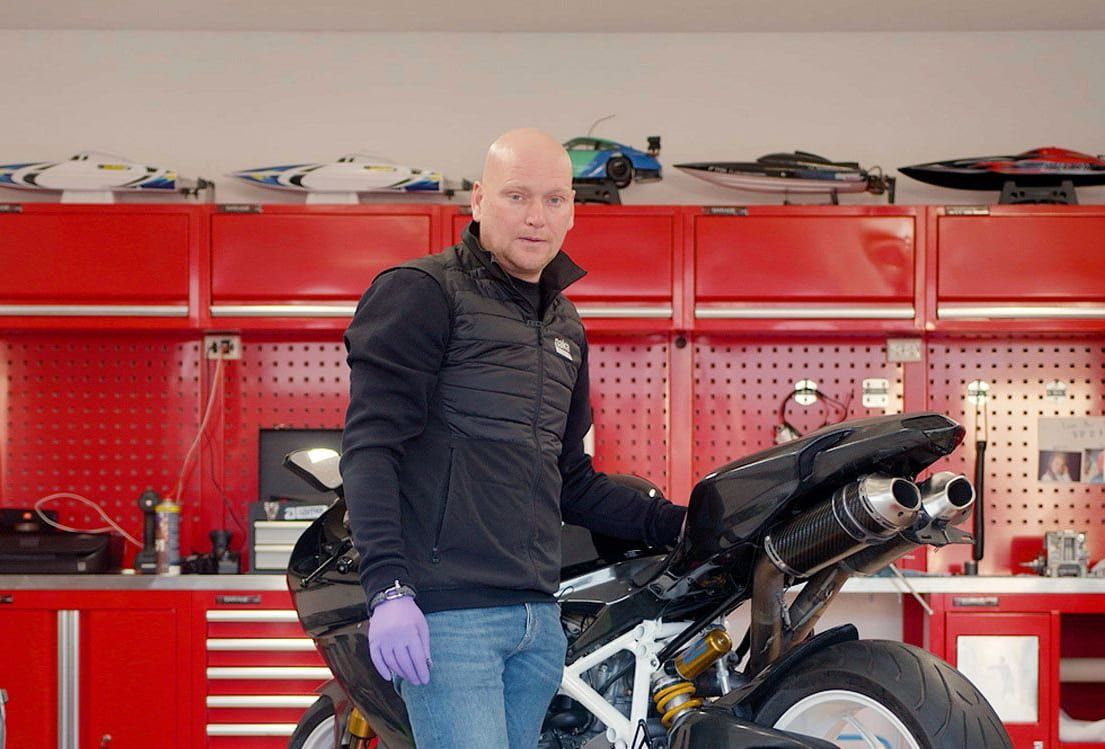 mann med en motorsykkel står inne i en garasje