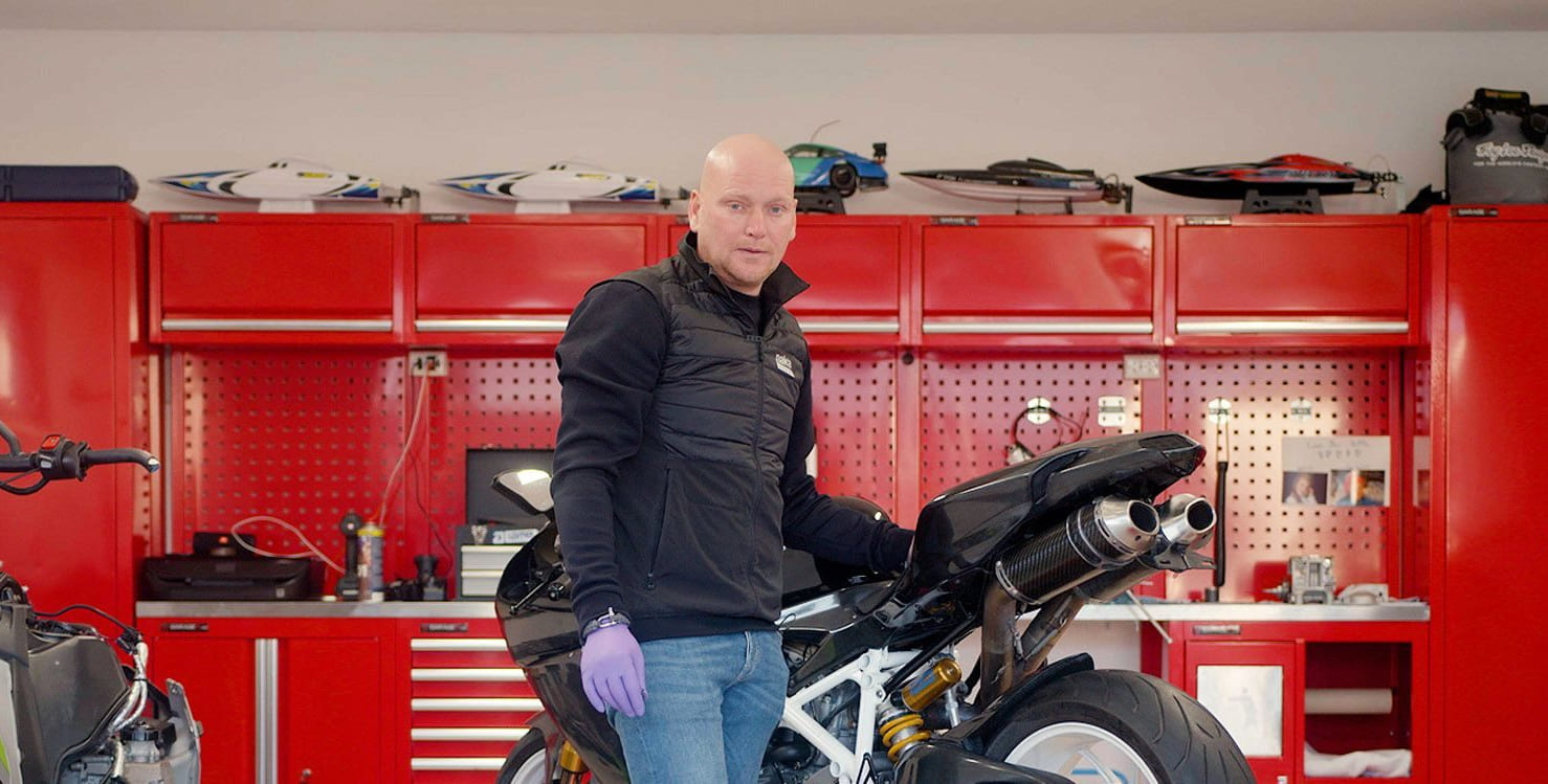 mann med en motorsykkel står inne i en garasje