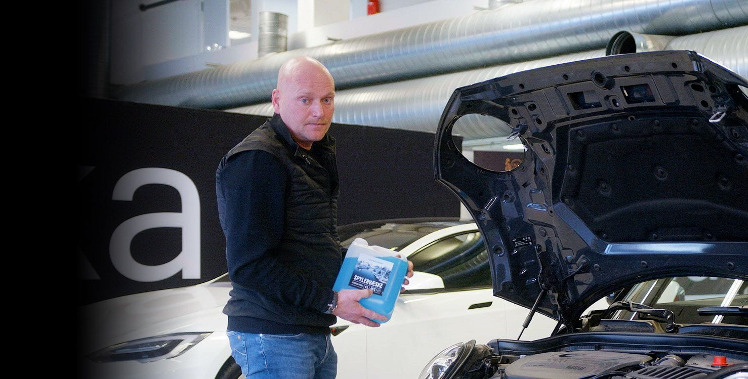 Mann fyller spylervæske på bilen sin