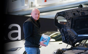 Mann fyller spylervæske på bilen sin