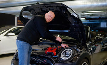 En mann kobler startkabler til bilbatteriet