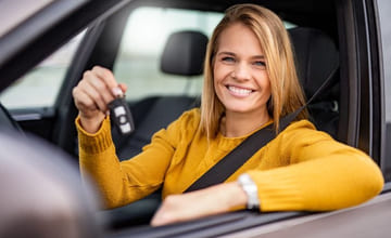 kvinne i sin nye bil smiler mens hun holder opp bilnøklene