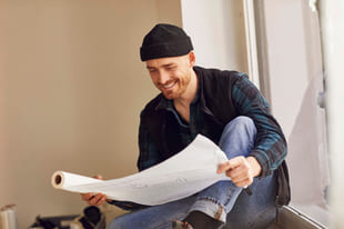 mann med lue leser en plan over arkitekturen