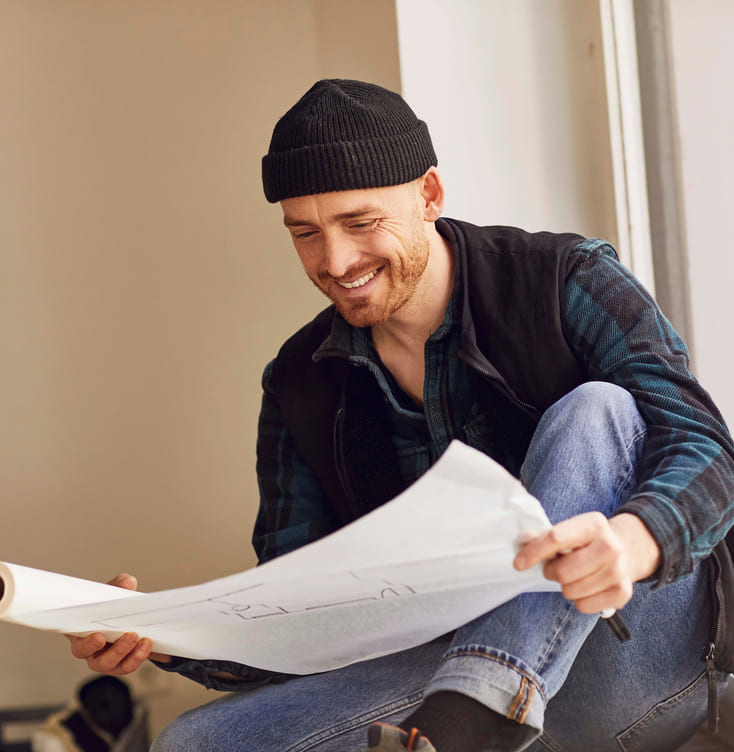 mann med lue leser en plan over arkitekturen