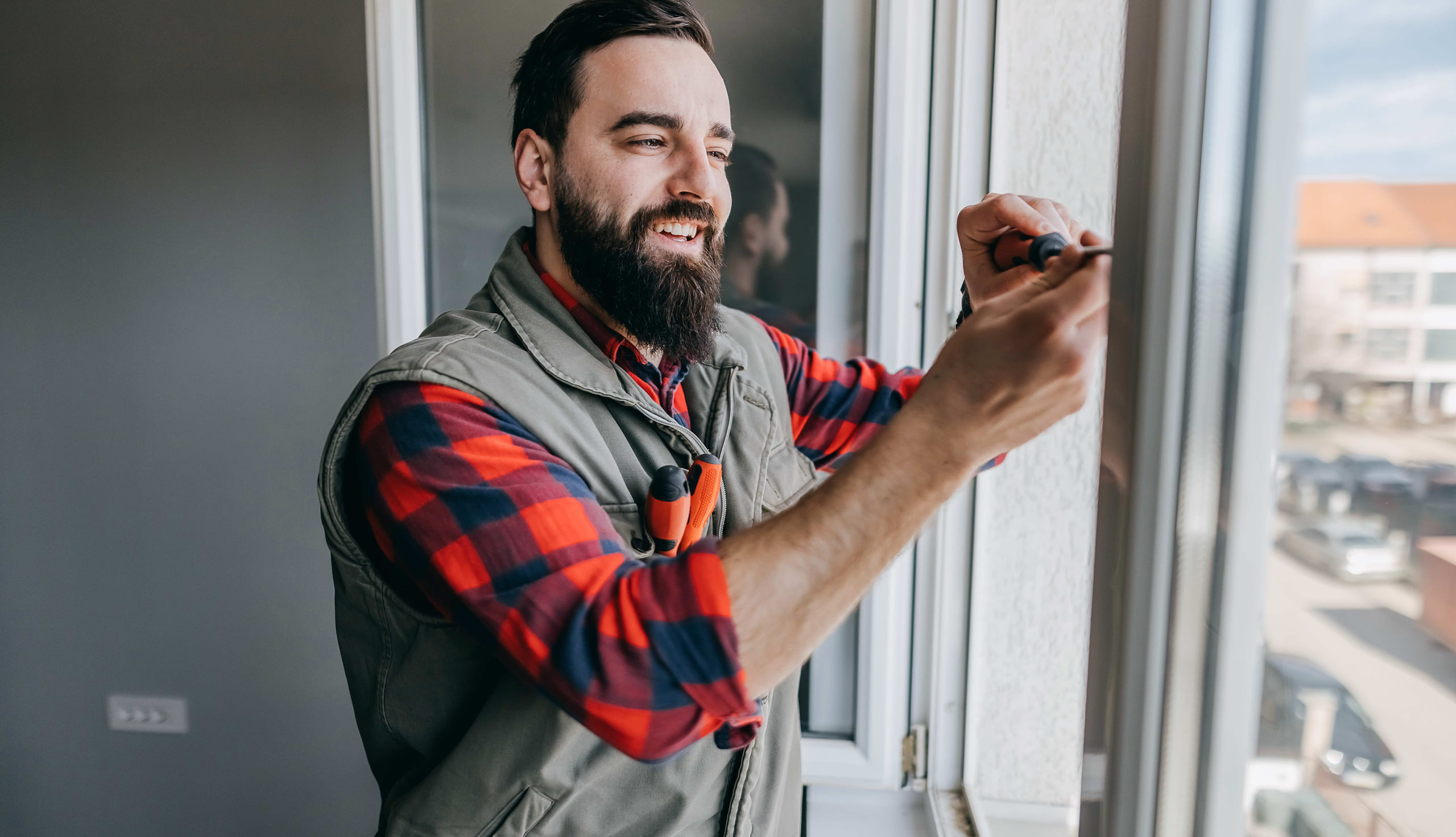 en mann i rutete skjorte skrur i et vindu