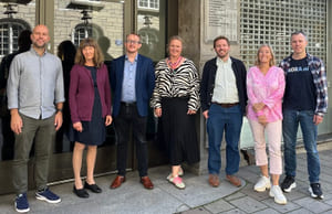 Foto av syv personer stående foran en husvegg. Foto av ekspertgruppe